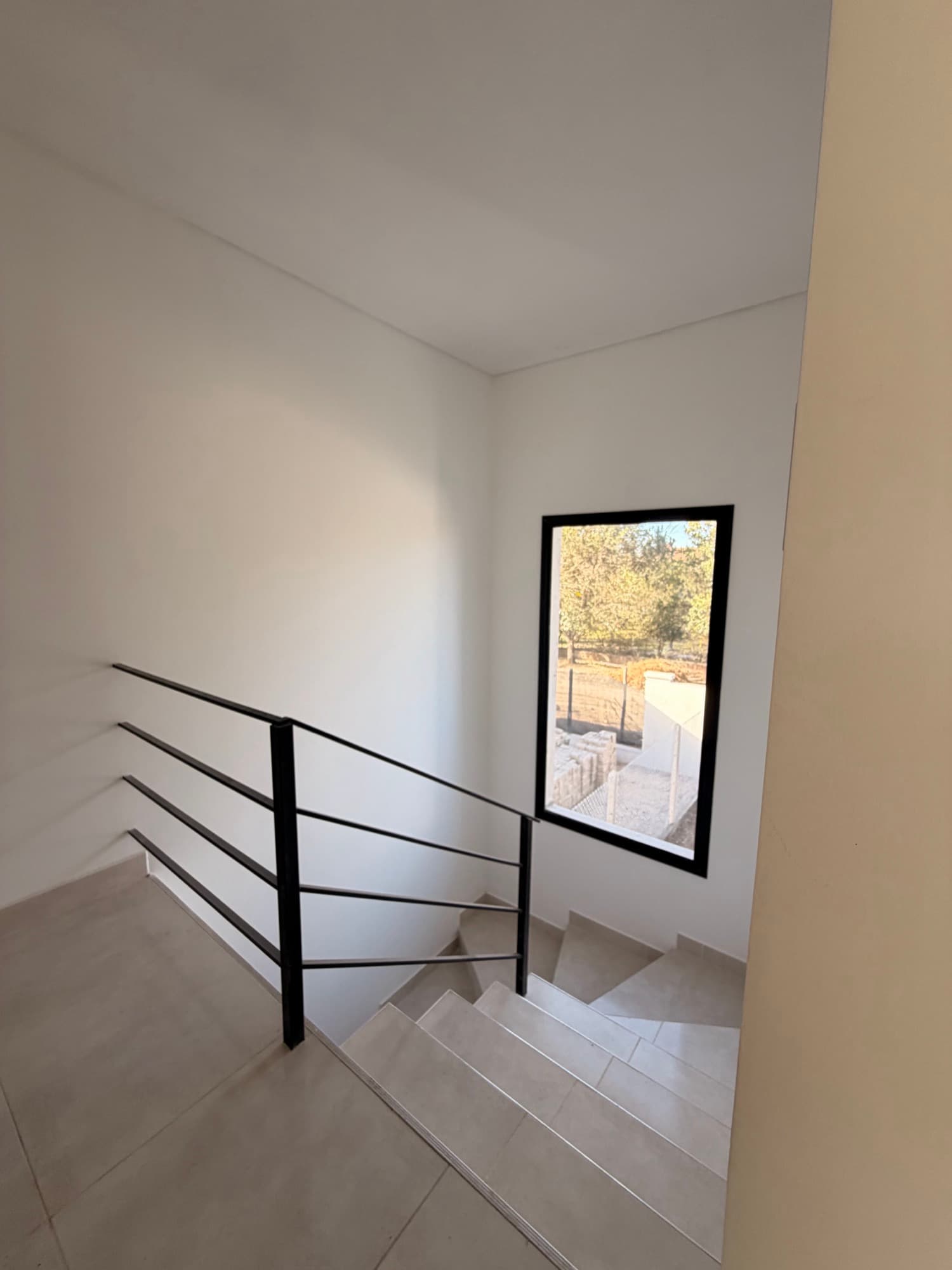 Escalera interior con baranda metálica y ventana al exterior